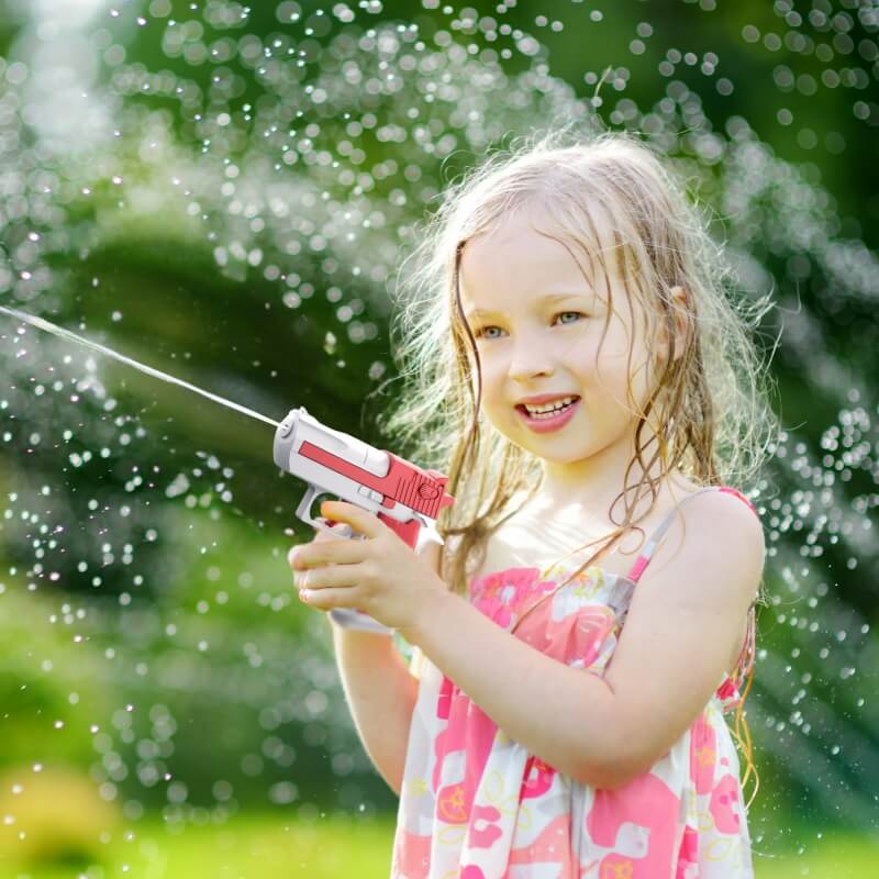 une-fille-heureuse-joue-a-la-bataille-d'eau-dehors-avec-son-mini-pistolet-a-eau-rouge-et-blanc