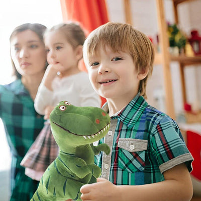 un-garçon-joyeux-tenant-une-peluche-dinosaure-vert-dans-ses-mains