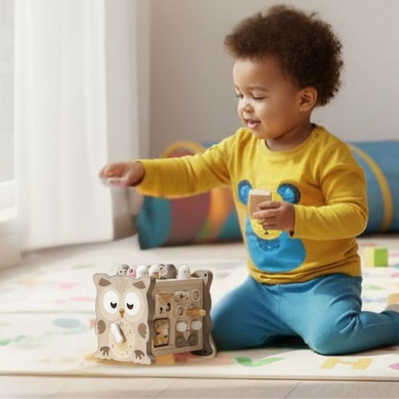 cube d'éveil bébé qui joue dans le salon portant un chandail jaune et pantalon bleu