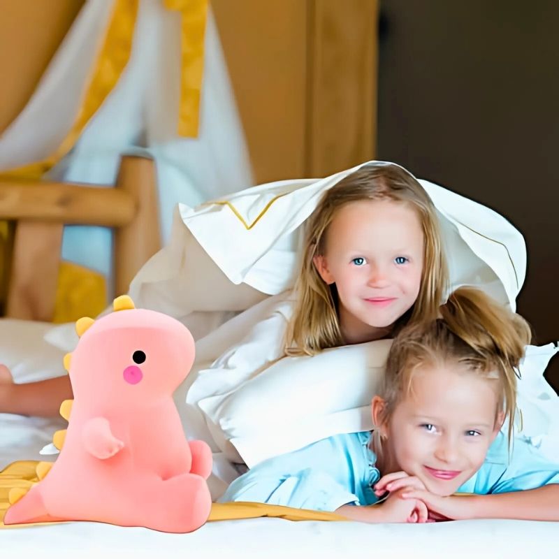 deux fillettes sur lit blanc avec leur peluche dinosaure rose