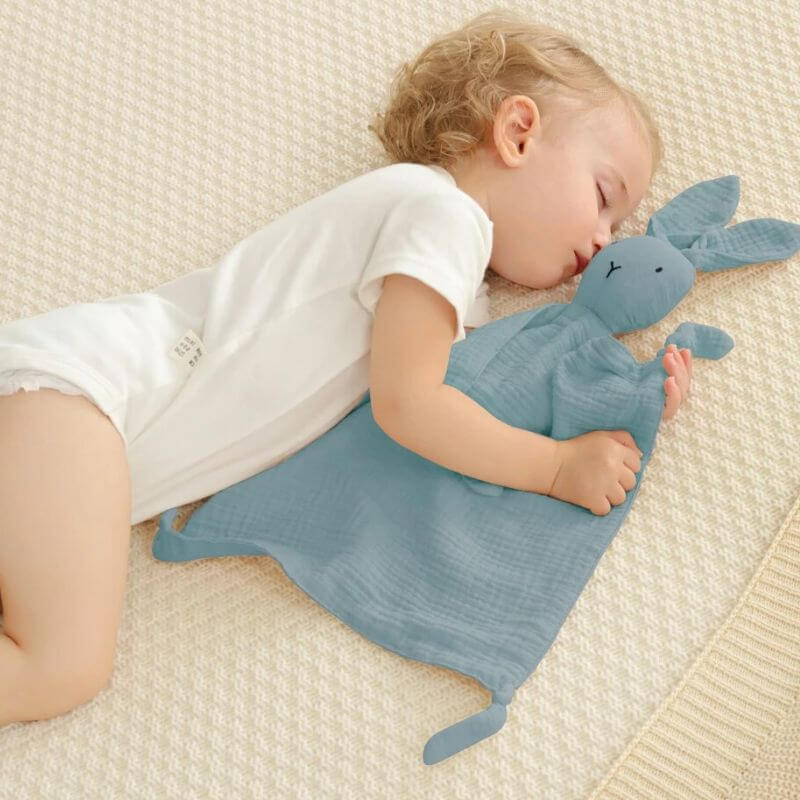 doudou-lapin-gris-bleu-dans-les-bras-d_un-bebe-qui-dort-paisiblement-sur-le-cote