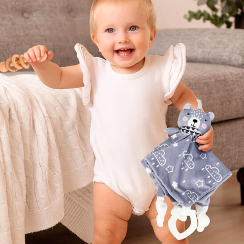 ourson-en-peluche-avec-pièce-de-tissu-carrée-dans-la-main-d'un-bebe-fille-tres-heureuse-au-grand-sourire