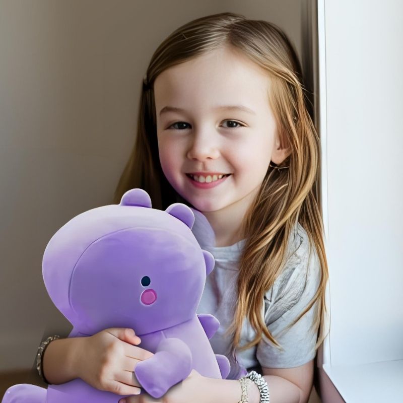 fillette 6 ans joyeuse avec sa peluche dinosaure mauve
