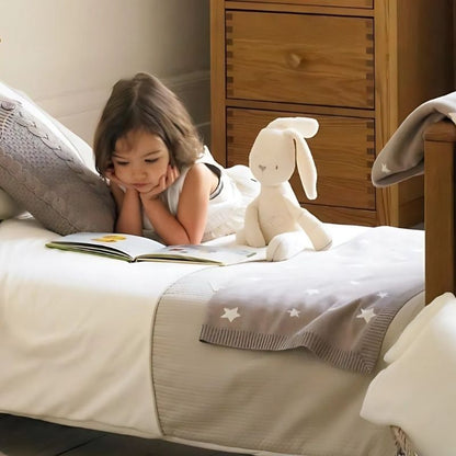 fillette sur son lit avec sa peluche lapin blanc