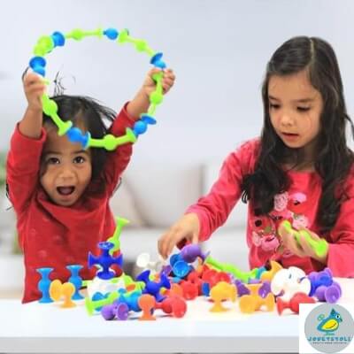 deux-fillettes-joyeuses-jouant-avec-leur-jouets-à-la-table